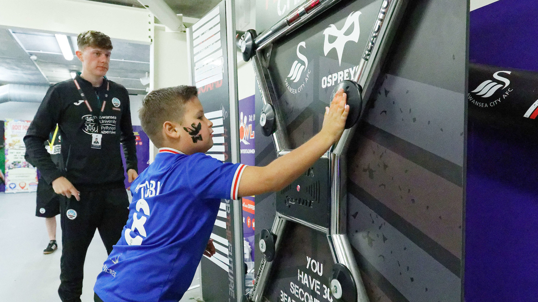 Child in Swans shirt plays the batak machine